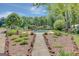 Backyard pool area, bordered by greenery, rock paths, and lush landscaping with distant view of the house at 1572 Hines Rd, Moreland, GA 30259