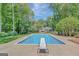 Backyard pool boasts a diving board and is surrounded by mature trees, offering a private oasis at 1572 Hines Rd, Moreland, GA 30259