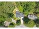 A bird's eye view of a home with a large driveway, manicured lawn, mature trees and a fenced yard at 1850 Linnet Ne Ct, Roswell, GA 30075