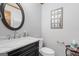 Elegant half bath with a black vanity, marble countertop, round mirror, and decorative accents at 1850 Linnet Ne Ct, Roswell, GA 30075