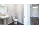 Half bathroom featuring a sleek pedestal sink, round mirror, and modern fixtures at 609 Lobelia Way, Locust Grove, GA 30248
