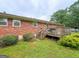 Brick home with wooden deck and stairs, surrounded by green lawn and mature trees at 5141 Hiram Lithia Springs Rd, Powder Springs, GA 30127