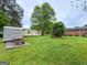 Spacious backyard featuring mature trees, sheds, and a picnic table, perfect for outdoor gatherings at 5141 Hiram Lithia Springs Rd, Powder Springs, GA 30127
