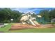 A large playground with multiple slides, climbing structures, and a basketball court surrounded by lush greenery at 7314 Basalt Dr, Union City, GA 30291