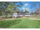 Backyard showcasing a lush lawn, mature trees, and the rear elevation of the home with a screened porch at 308 Lee Thompson Rd, Moreland, GA 30259