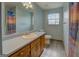 Bathroom with wood cabinets, large mirror, full counter, vinyl floor, shower-tub, toilet, and window at 2809 South Ola Rd, Locust Grove, GA 30248