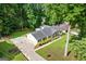 Aerial view of a charming single-story home with lush landscaping, a long driveway, and a welcoming covered front porch at 3210 Roseheath Ln, Lithonia, GA 30038