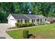 View of white brick home with black shutters, attached garage and long driveway at 3210 Roseheath Ln, Lithonia, GA 30038