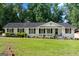 Exterior of this single-story home featuring white painted brick, black shutters and mature landscaping at 3210 Roseheath Ln, Lithonia, GA 30038