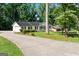 Charming single-story home featuring a long driveway, white brick, dark shutters, and lush landscaping at 3210 Roseheath Ln, Lithonia, GA 30038