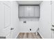 Well-lit laundry room featuring cabinets for ample storage and wood-look floors at 3210 Roseheath Ln, Lithonia, GA 30038