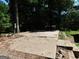 Patio with overgrown weeds sits amongst trees; possible foundation at 1306 Stonemont Rd, Auburn, GA 30011