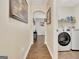 Hallway leading to the laundry room with white washer and dryer appliances and wooden floors at 395 Sylvan Loop, Fayetteville, GA 30214
