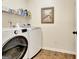 Bright laundry room with modern washer and dryer, shelving for supplies, and tiled floor at 395 Sylvan Loop, Fayetteville, GA 30214