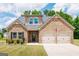 Charming brick home featuring a two-car garage and meticulously landscaped front yard with stone accents at 1225 Hibiscus Way, Mcdonough, GA 30253