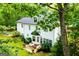 A white two story house with a black roof is surrounded by lush green foliage at 97 Coral Dr, Whitesburg, GA 30185