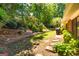 Landscaped backyard featuring mature trees, flowers, grass, and stepping stones at 105 Lake Forest Drive, Peachtree City, GA 30269