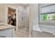 Bathroom featuring a soaking tub, a glass-enclosed shower, and a large walk-in closet at 234 Thyme Leaf Way, Locust Grove, GA 30248