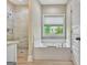 Bright bathroom featuring a soaking tub beneath a window and a separate glass-enclosed shower at 234 Thyme Leaf Way, Locust Grove, GA 30248