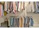 Organized walk-in closet with shelves and hanging rods filled with various clothing items at 234 Thyme Leaf Way, Locust Grove, GA 30248