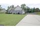 Expansive driveway leads to a charming home with well-maintained landscaping and a large, inviting front lawn at 234 Thyme Leaf Way, Locust Grove, GA 30248