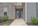 Close up view of a charming entrance with a stylish front door and stone accents, framed by lush landscaping at 234 Thyme Leaf Way, Locust Grove, GA 30248
