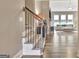 View of the staircase featuring painted risers and iron spindles, leading into a bright and open living space at 234 Thyme Leaf Way, Locust Grove, GA 30248