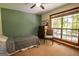 Green bedroom with a ceiling fan, large window, and a decorative dresser for a relaxing, nature-inspired room at 1655 Stacia Dr, Covington, GA 30016