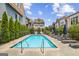 Community pool surrounded by lounge chairs, greenery, and attractive townhomes on a bright and sunny day at 1058 Kirkland Cir, Smyrna, GA 30080