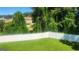 Backyard view with green lawn and white fence, with trees and shrubbery in background at 6120 Raleigh Oaks Ct, Lithonia, GA 30058