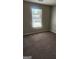 This bedroom features a neutral color scheme, soft carpeting, and a bright window for natural light at 6120 Raleigh Oaks Ct, Lithonia, GA 30058