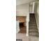 View of the carpeted staircase leading to the upper level, with a glimpse of the living area featuring a cozy brick fireplace at 6120 Raleigh Oaks Ct, Lithonia, GA 30058