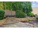 Backyard featuring a stone retaining wall and steps leading to an upper area with mulch and mature trees at 750 Highview Ct, Woodstock, GA 30189