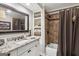 Bathroom featuring granite counters, white cabinets, a large mirror and a tub-shower combo with brown tiling at 750 Highview Ct, Woodstock, GA 30189
