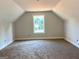 A carpeted attic space illuminated by a window, showcasing the room's potential at 1705 Lake Dow Rd, Mcdonough, GA 30252