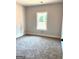 This bedroom features neutral walls, carpet, and a bright window overlooking trees at 1705 Lake Dow Rd, Mcdonough, GA 30252