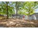 Expansive backyard with mature trees, a gray home, and a shed with an orange door at 5180 Ash St, Forest Park, GA 30297