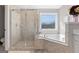 Bathroom featuring walk-in shower with tile surround and soaking tub under a window at 130 Edgewater Trl, Fayetteville, GA 30215