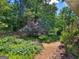 Backyard with gravel paths, lush greenery, and mature trees, provides a serene setting at 264 Keller Dr, Mcdonough, GA 30252