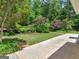 Exterior view of the backyard featuring a grassy lawn, a concrete driveway, and mature trees at 264 Keller Dr, Mcdonough, GA 30252