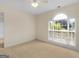 Carpeted beige bedroom with ceiling fan and a large window with a view of lush backyard greenery at 264 Keller Dr, Mcdonough, GA 30252