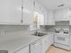 Bright kitchen boasts white cabinets, countertops, and a stainless steel sink under a window at 264 Keller Dr, Mcdonough, GA 30252
