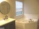 Bright bathroom featuring a large soaking tub with white tile backsplash at 7564 Mountain Ridge Ln, Lithonia, GA 30058