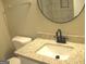 Modern bathroom with granite countertop, sleek faucet, and a circular mirror at 7564 Mountain Ridge Ln, Lithonia, GA 30058