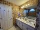 Traditional bathroom featuring a double sink vanity with floral wallpaper accents at 5627 Isleworth Ct, Atlanta, GA 30349