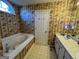 Bathroom featuring a soaking tub with jacuzzi jets and patterned wallpaper at 5627 Isleworth Ct, Atlanta, GA 30349