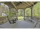 Covered porch area with a hanging swing, and seating with a wooded view at 1000 Pleasance Grv, Peachtree City, GA 30269