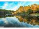 Reflective lake view showing a wooded dock, trees, and a partly cloudy sky, ideal for serene living at 606 Ridgelake Dr, Peachtree City, GA 30269