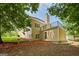 Back of the home with a balcony overlooking a tree-filled backyard and landscaped yard at 115 Blue Grass Way, Oxford, GA 30054