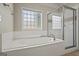 Bathroom featuring a jetted tub, tiled surround, shower and privacy window at 115 Blue Grass Way, Oxford, GA 30054